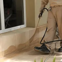 General pest control technician spraying exterior perimeter around a home in Boise, ID