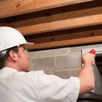 Termite inspection technician checking a basement wall and framing for termite activity in Boise, ID